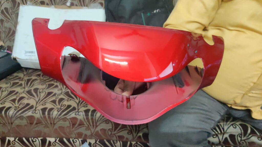 Tvs scooty headlight visor mask fairing in red color displayed on a clean background