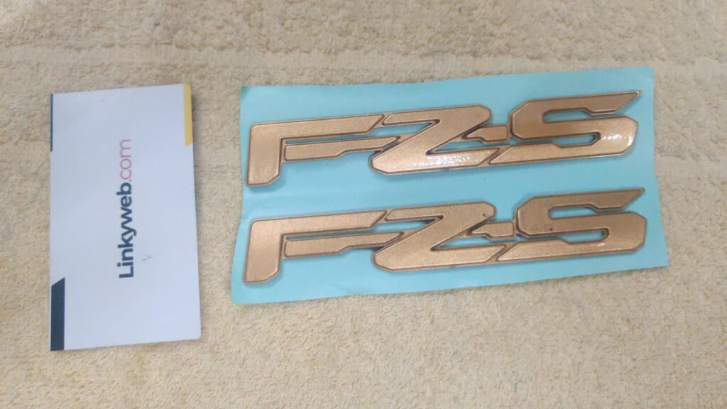 Close-up view of the premium yamaha fz s golden logo accessory for motorcycles